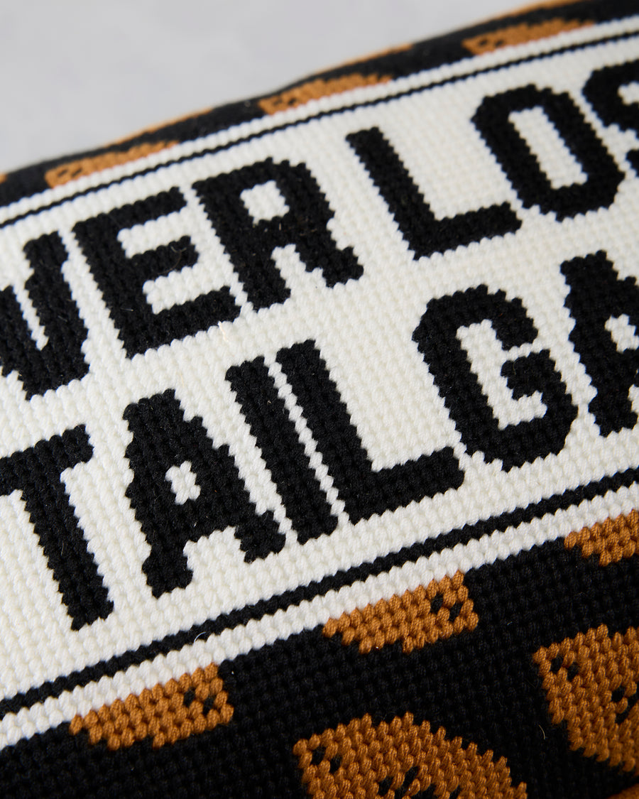 Close-up of the needlepoint lettering and black-and-orange patterned border on the tailgate pillow.