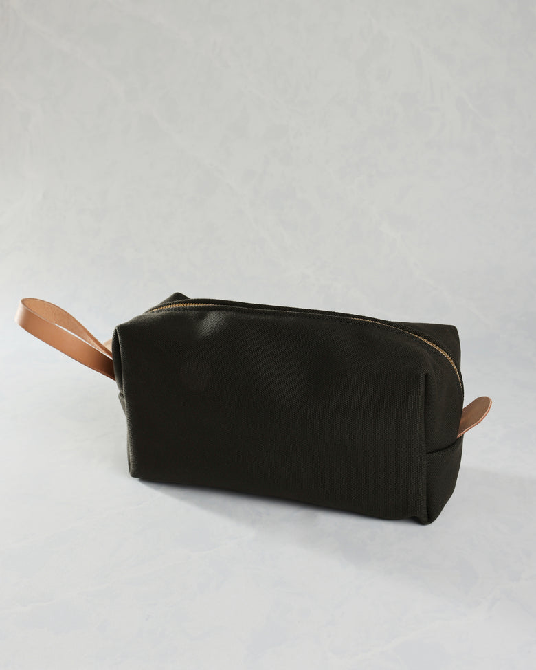 Closed black canvas travel kit with tan leather zipper pulls on both sides.