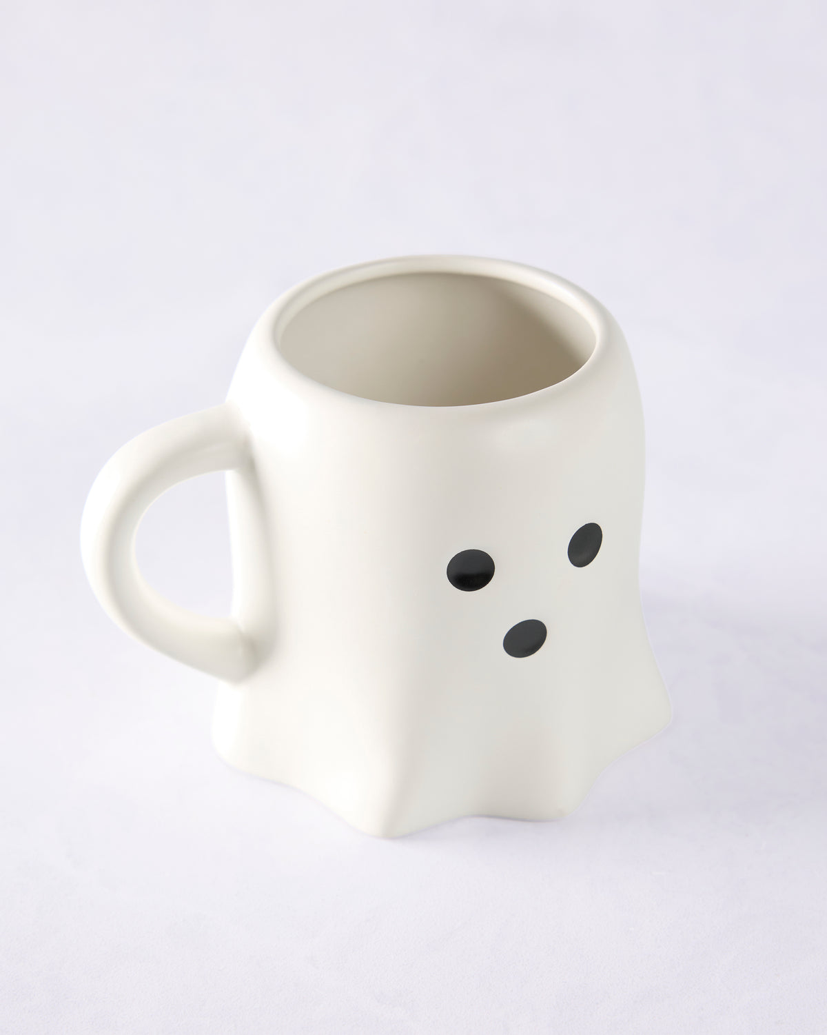 White ceramic ghost mug with a handle and three black oval face details.