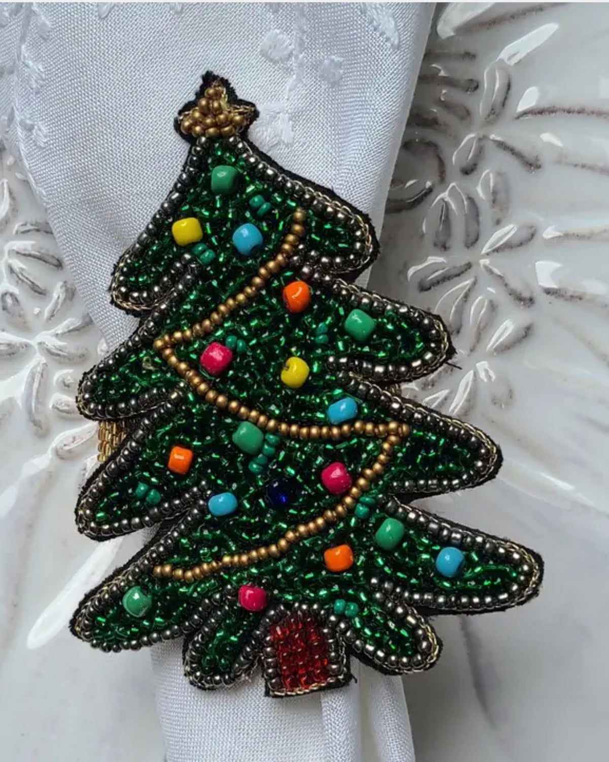 Beaded Christmas tree napkin ring with green foliage, multicolored ornaments, and a gold bead garland