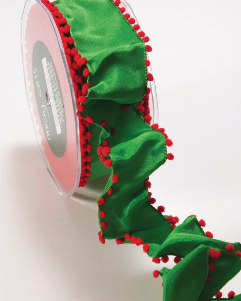 Green ribbon with red pom-pom edging shown partially unrolled beside its spool.