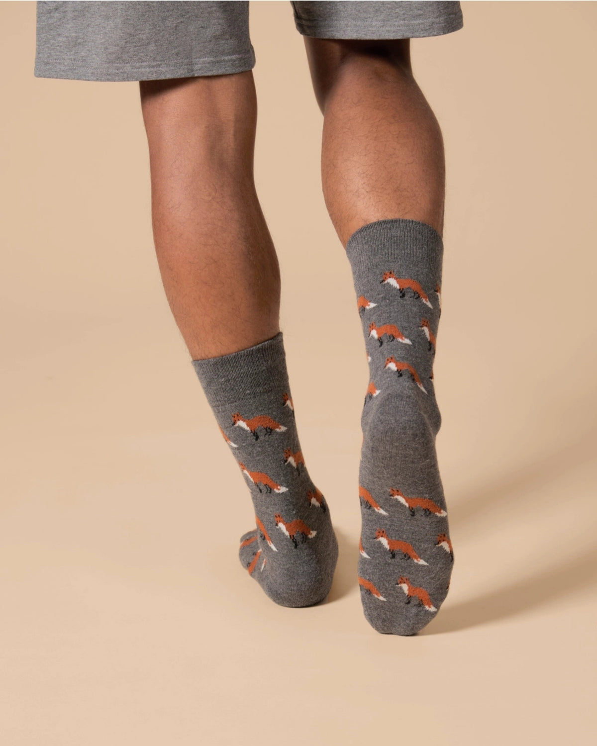 Gray crew socks with repeated fox motifs shown being worn on lower legs and feet.