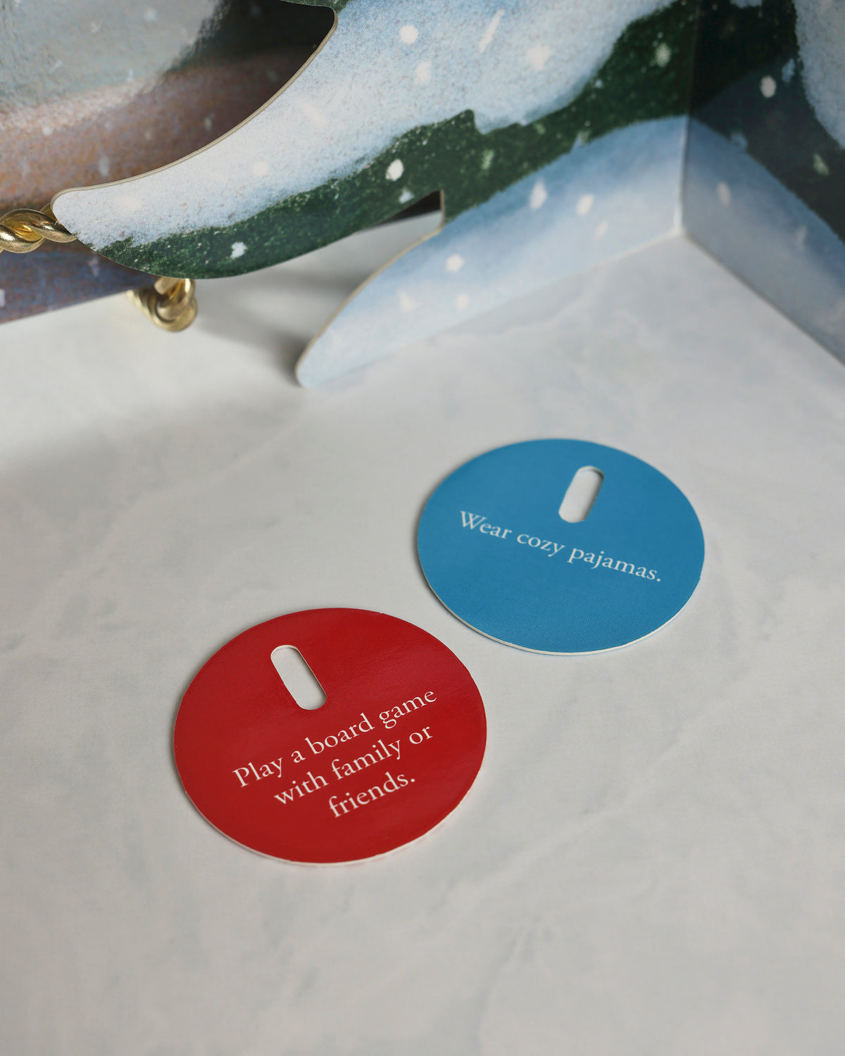 Close-up of two circular activity cards from the Polar Express countdown set: one says “Wear cozy pajamas” and the other says “Play a board game with family or friends.”