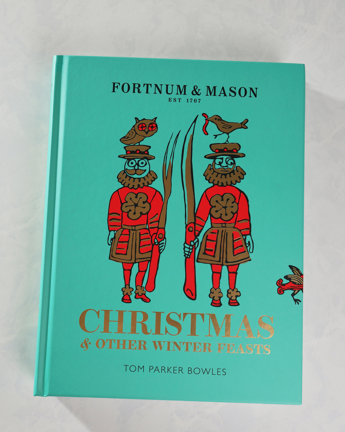 Front cover of Fortnum & Mason Christmas & Other Winter Feasts in teal, illustrated with two figures carrying oversized utensils.