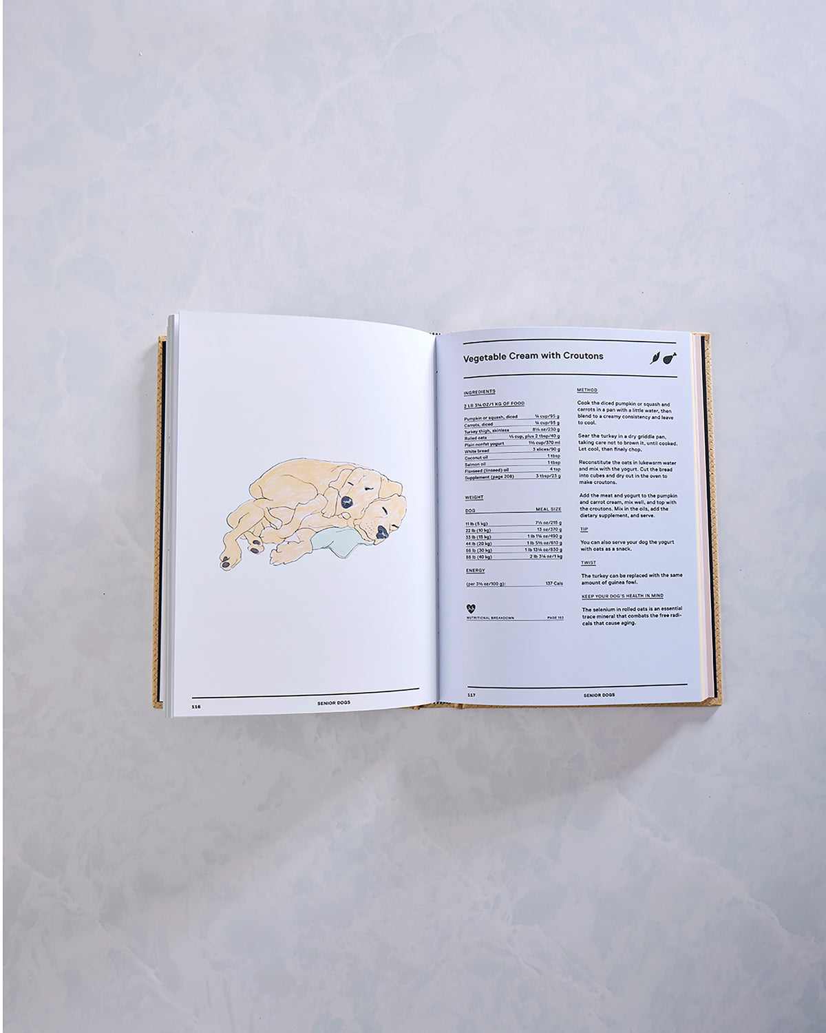 Feed Me cookbook opened to a Vegetable Cream with Croutons recipe, with a dog illustration on the facing page.