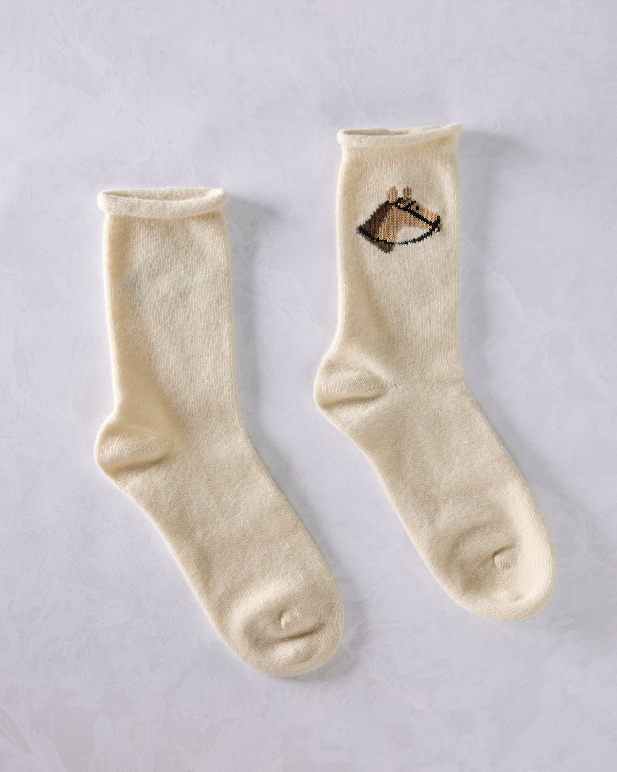 Two ivory crew socks displayed side by side; one shows a horse head embroidery near the top.