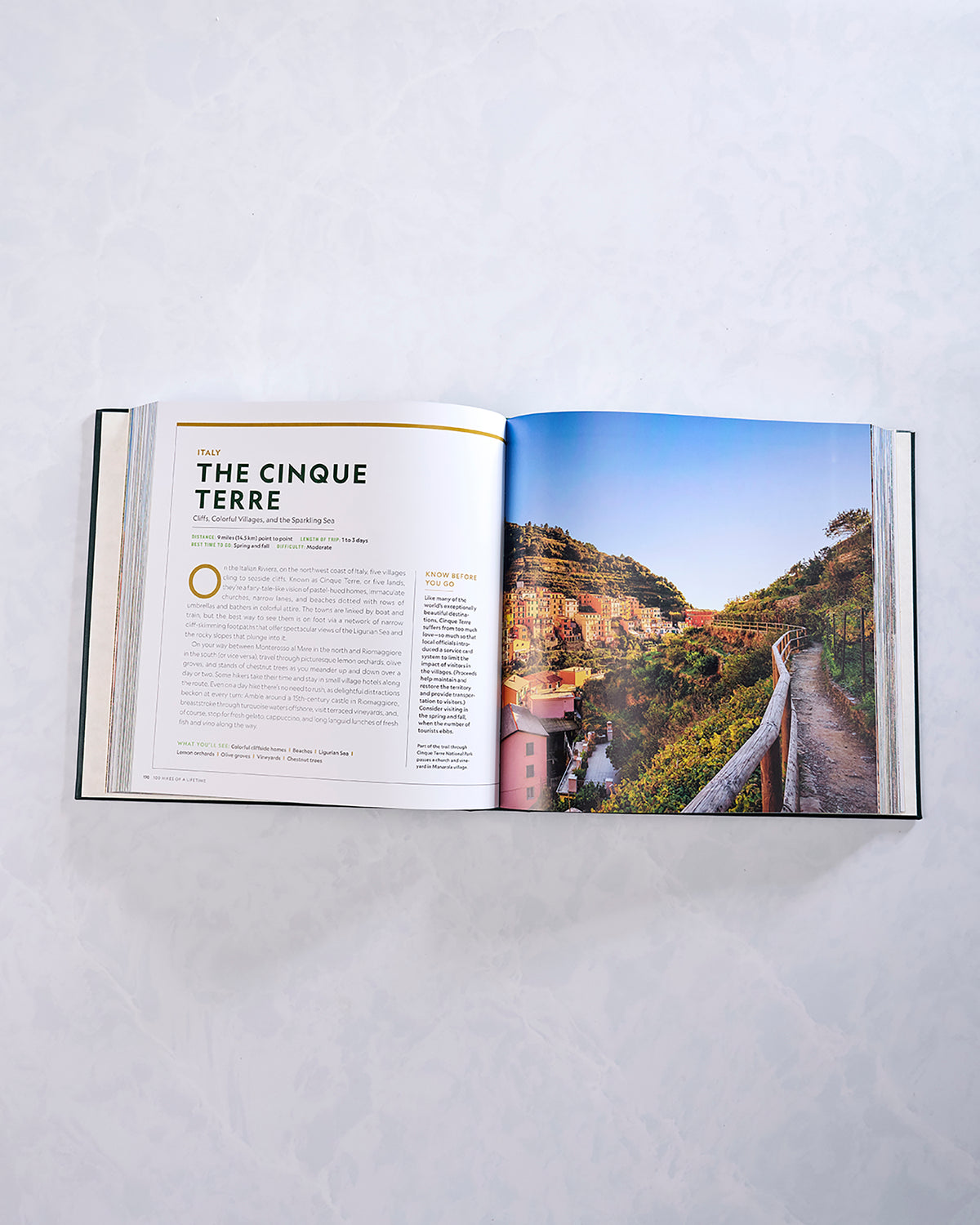 Open spread from the hiking book featuring a Cinque Terre entry and a coastal hillside village photograph.