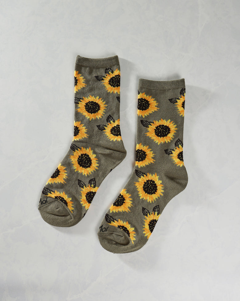 Pair of olive crew socks displayed separately with an all-over yellow sunflower and black leaf pattern.