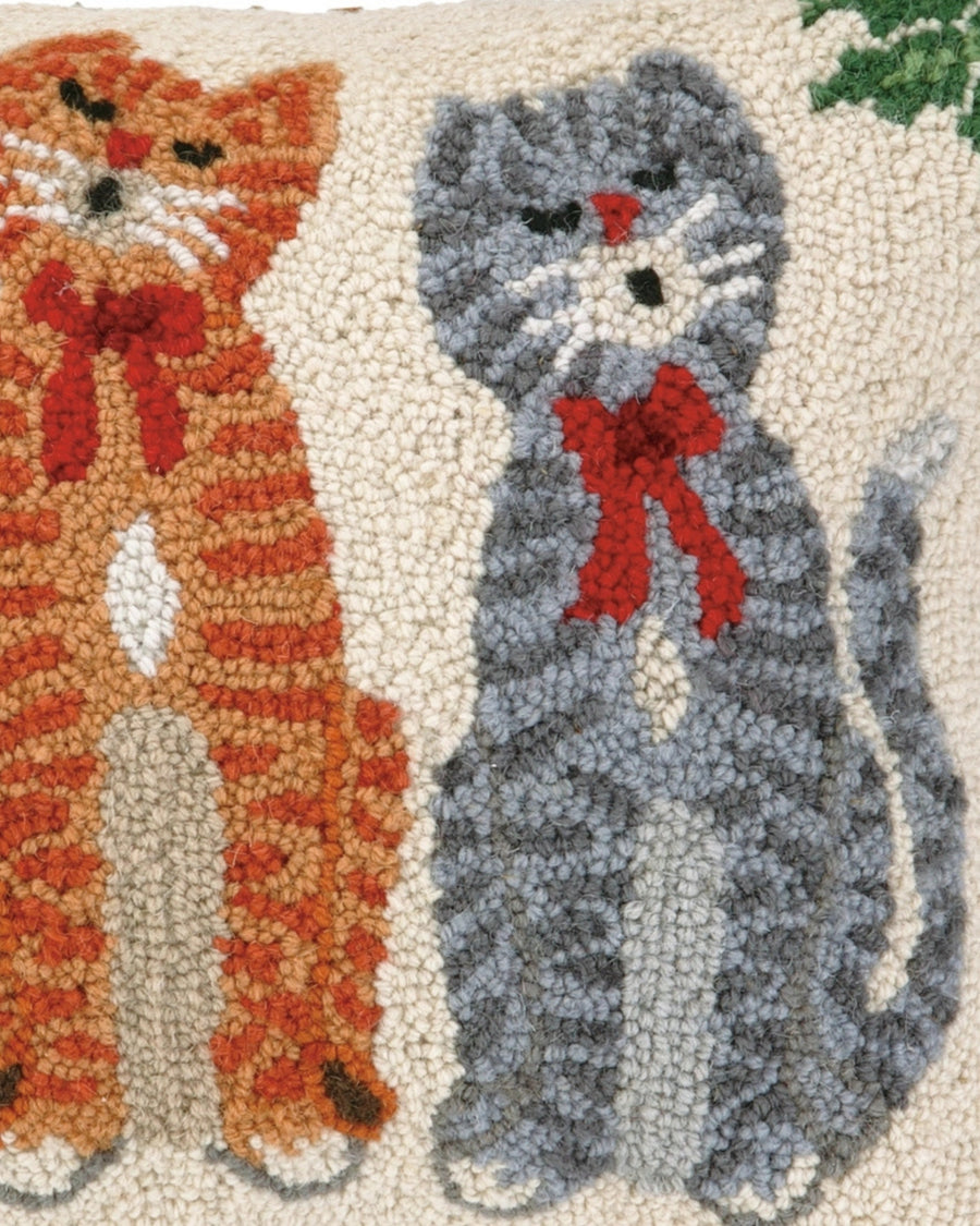 Close-up of the hooked front of the Caroling Cats pillow, showing gray and orange cats with red accents on an ivory background.