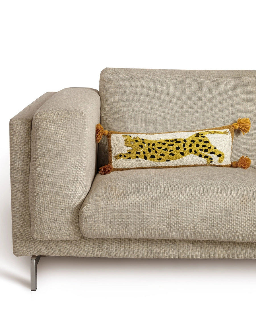 Chi Chi hook pillow with a spotted leopard design displayed on a beige sofa.