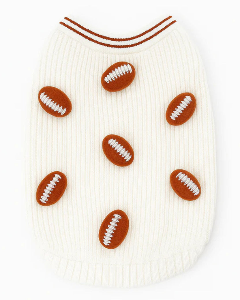 Front view of an ivory dog sweater with six brown football appliqués
