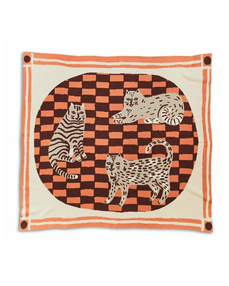 Knit throw blanket with three illustrated cats on an orange-and-brown checkerboard panel and a striped border.