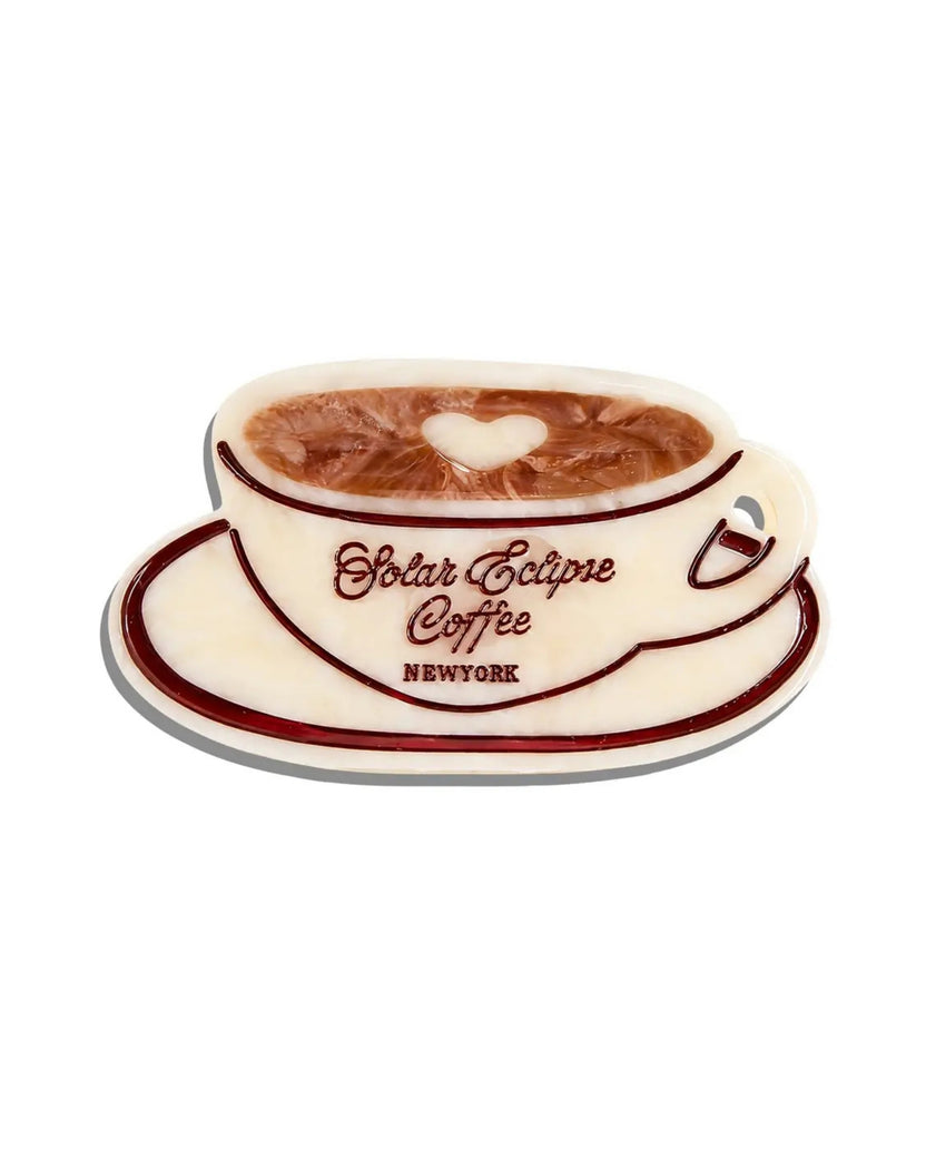Front view of an ivory coffee-cup-shaped claw hair clip with brown trim and a heart-shaped latte design.