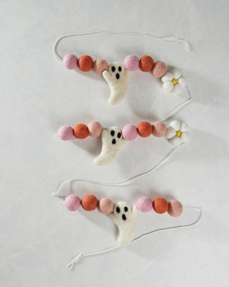 Pink, coral, and apricot felt garland with ghost shapes and white daisy accents, arranged in three strands.