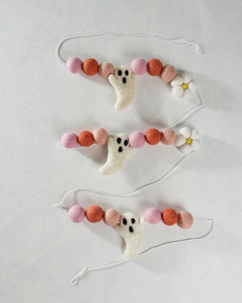 Pink, coral, and apricot felt garland with ghost shapes and white daisy accents, arranged in three strands.