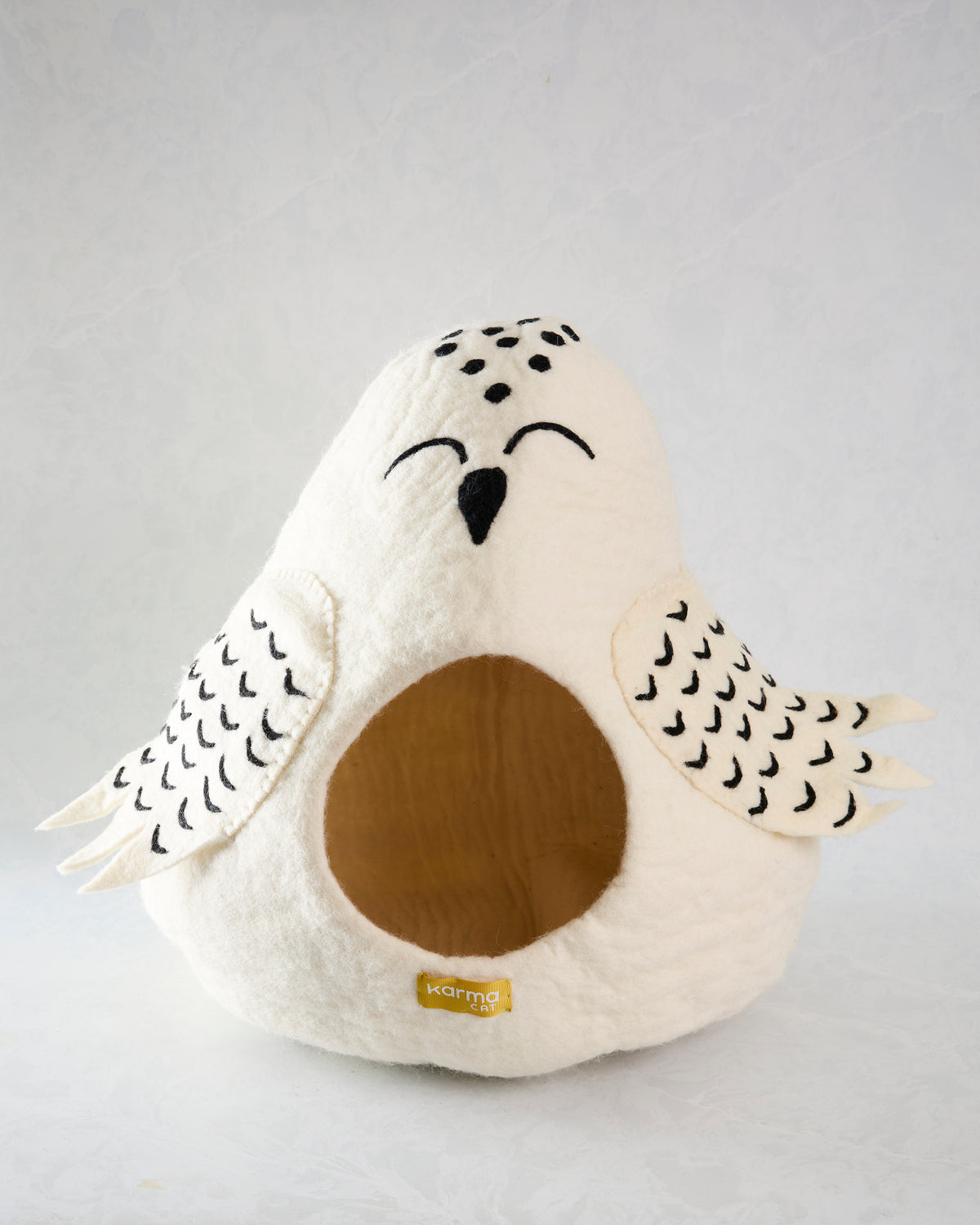Front view of the ivory owl pet cave with patterned wings, closed eyes, beak, and a round brown entrance.