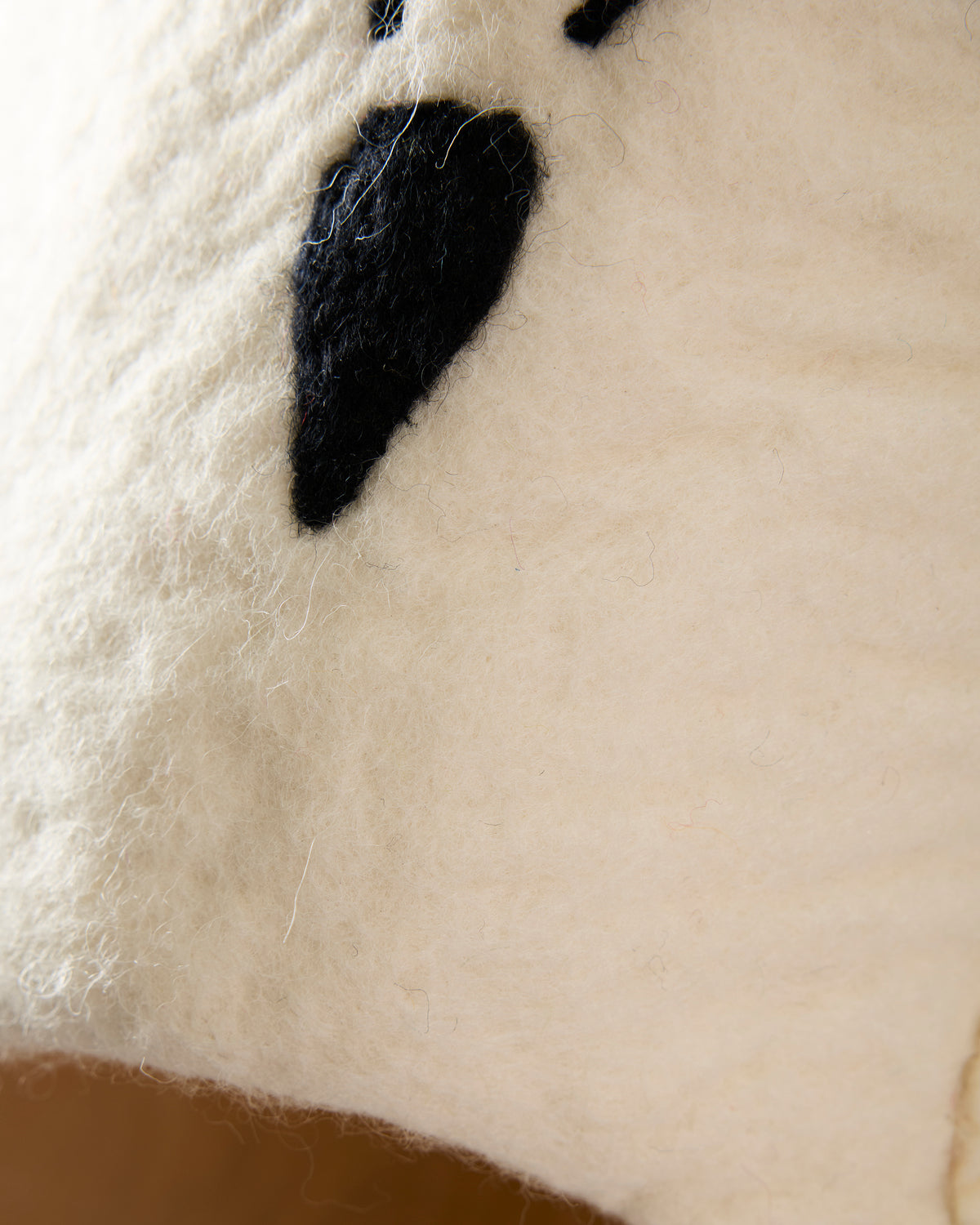 Close-up of the owl pet cave showing its black beak, ivory surface, and round brown entrance edge.