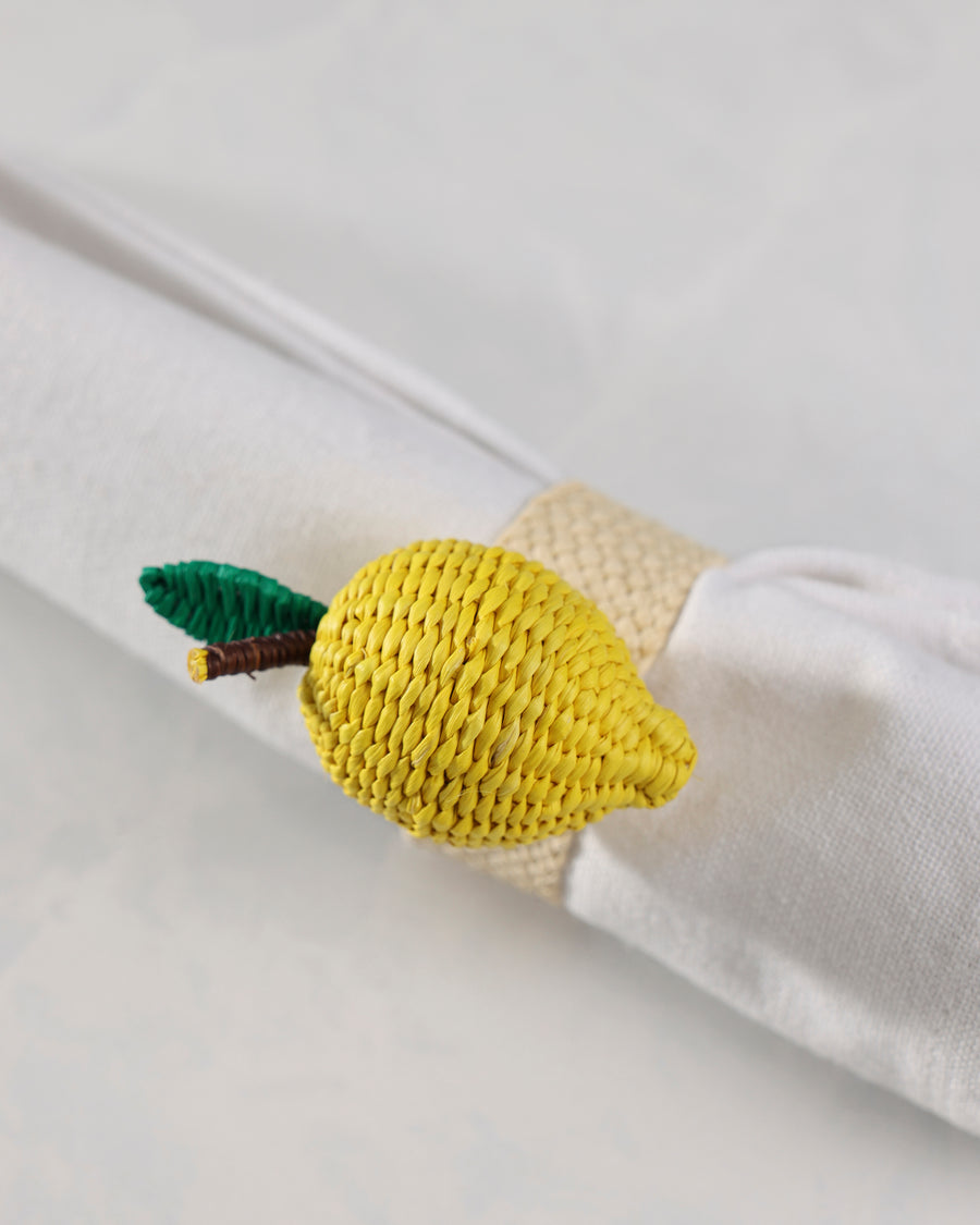 Close view of the yellow woven lemon napkin ring around a rolled white napkin.