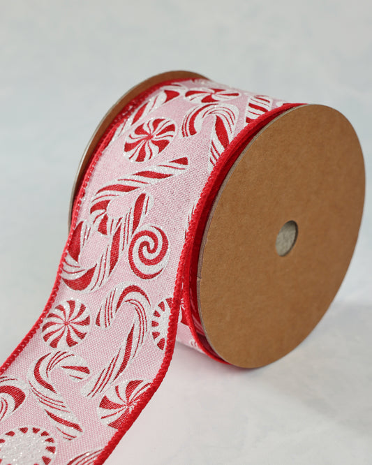 Roll of pink wired peppermint ribbon with red-and-white candy motifs and red edging.