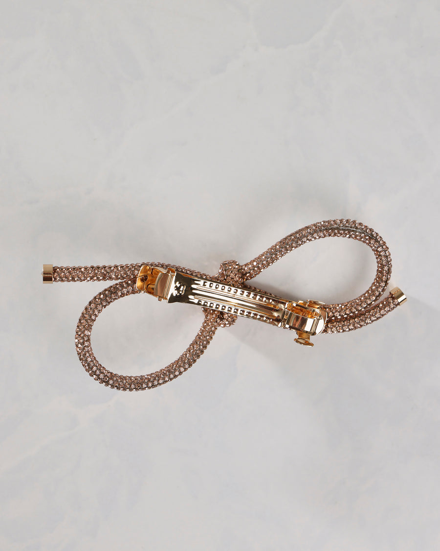 Underside view of the gold sparkling bow barrette showing its metal clasp and attached bow loops.