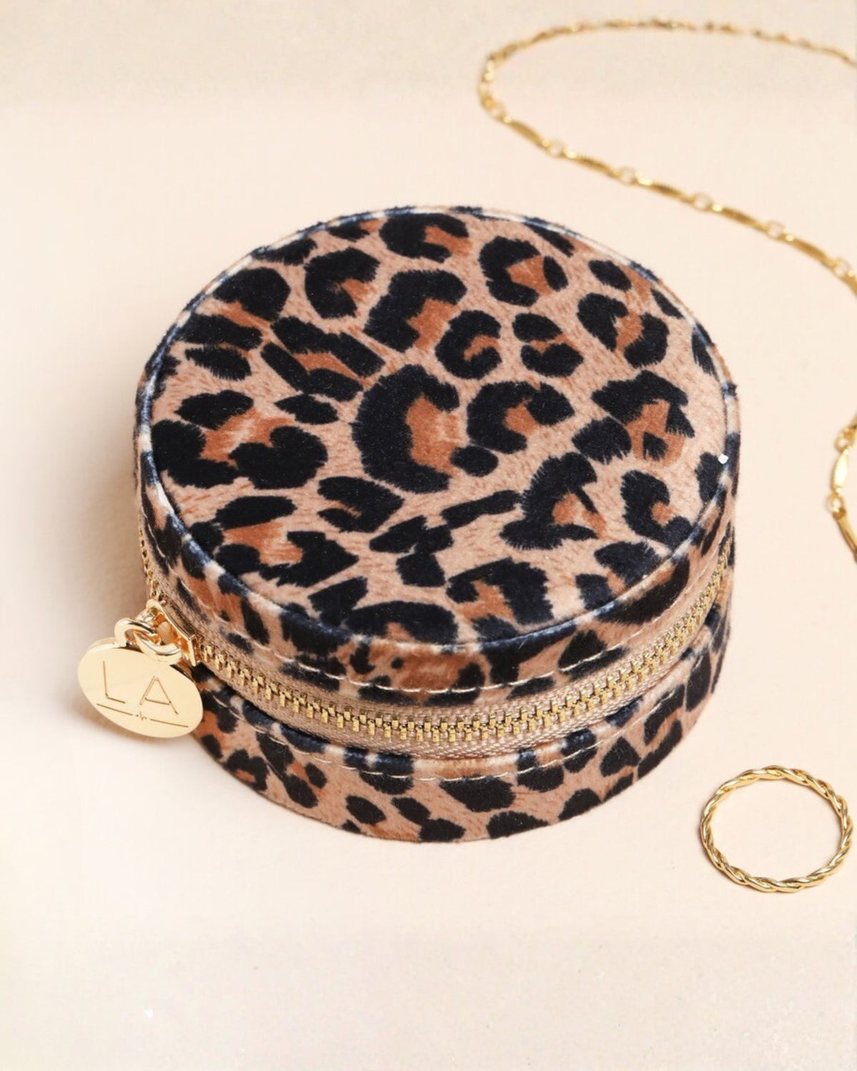 Closed round leopard-print velvet travel jewelry case with a gold zipper.