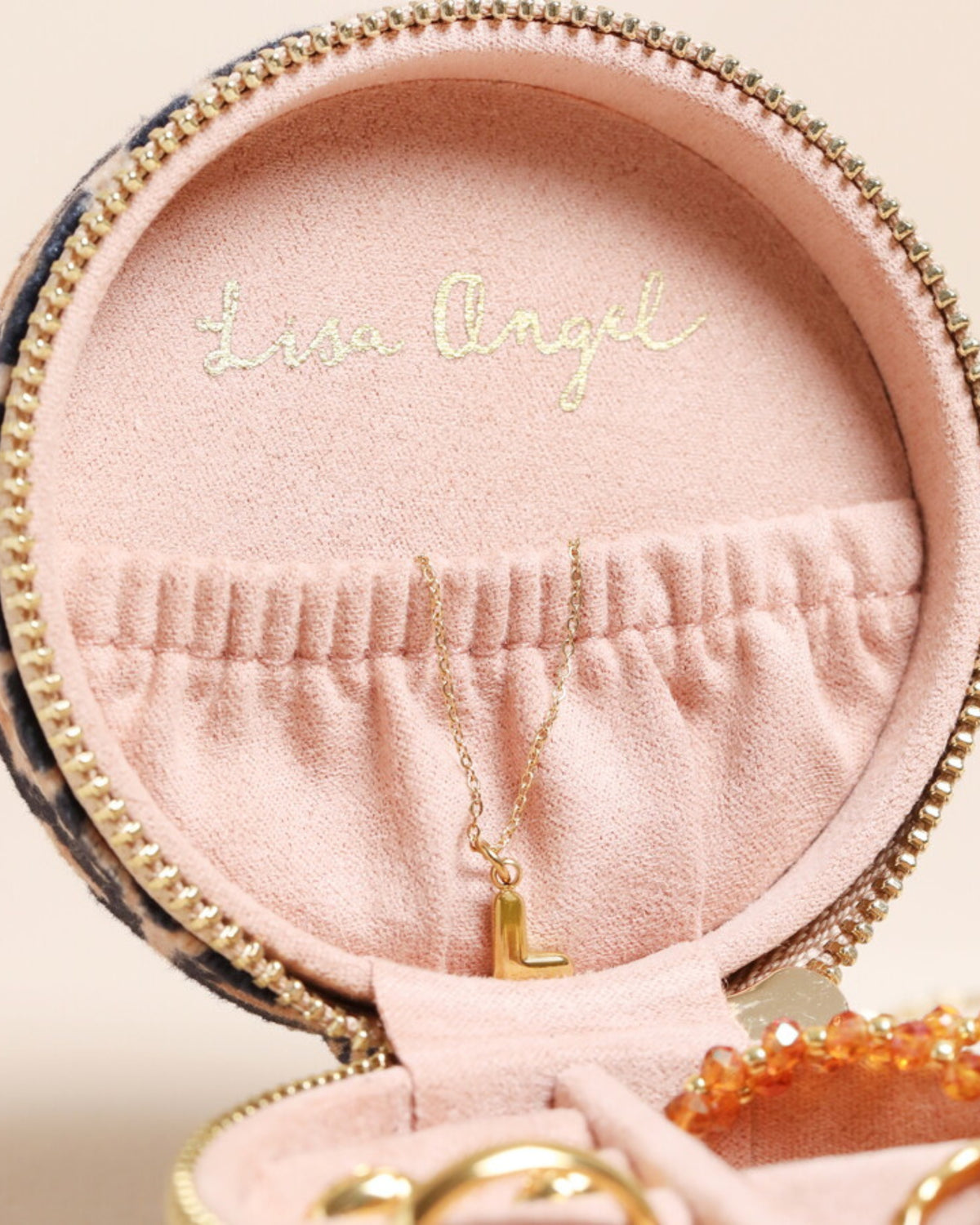 Open leopard-print round jewelry case showing pink interior compartments, a pendant necklace, and Lisa Angel branding inside the lid.