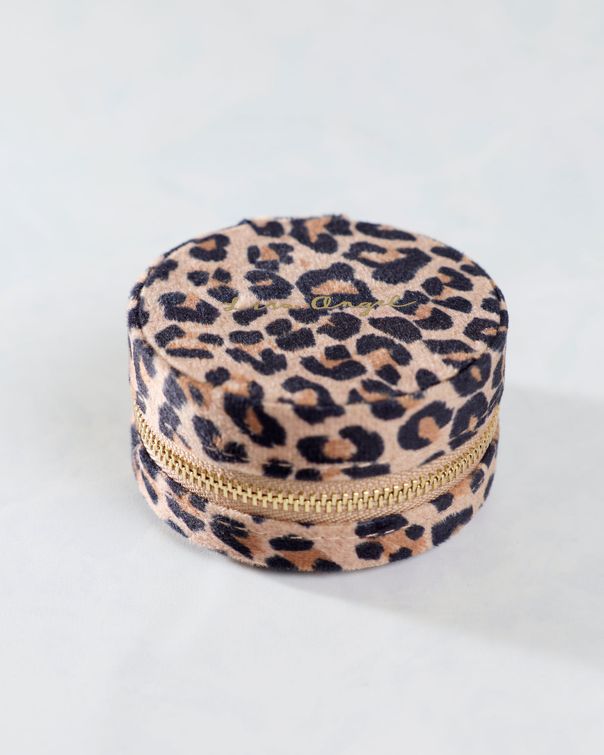 Closed round travel jewelry case with a leopard print exterior and gold zipper.