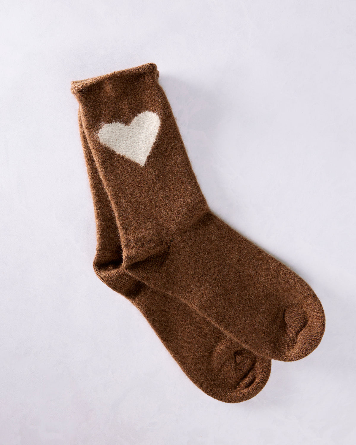 Brown crew socks with a white heart on the upper cuff, arranged overlapping on a light background.