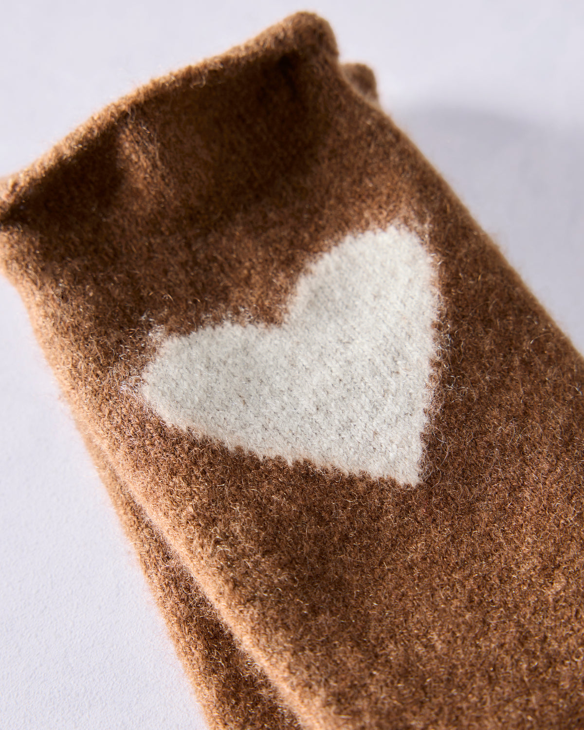 Close-up of a brown crew sock with a white heart motif.