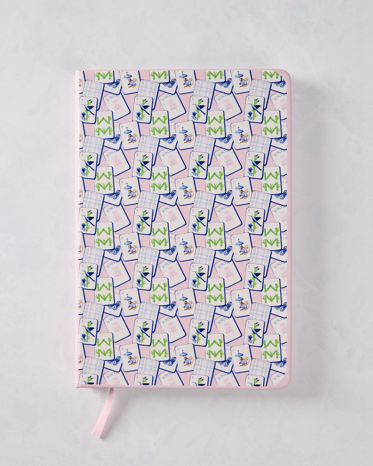Closed pink journal with a repeating multicolored mahjong tile cover pattern and a pink ribbon bookmark.