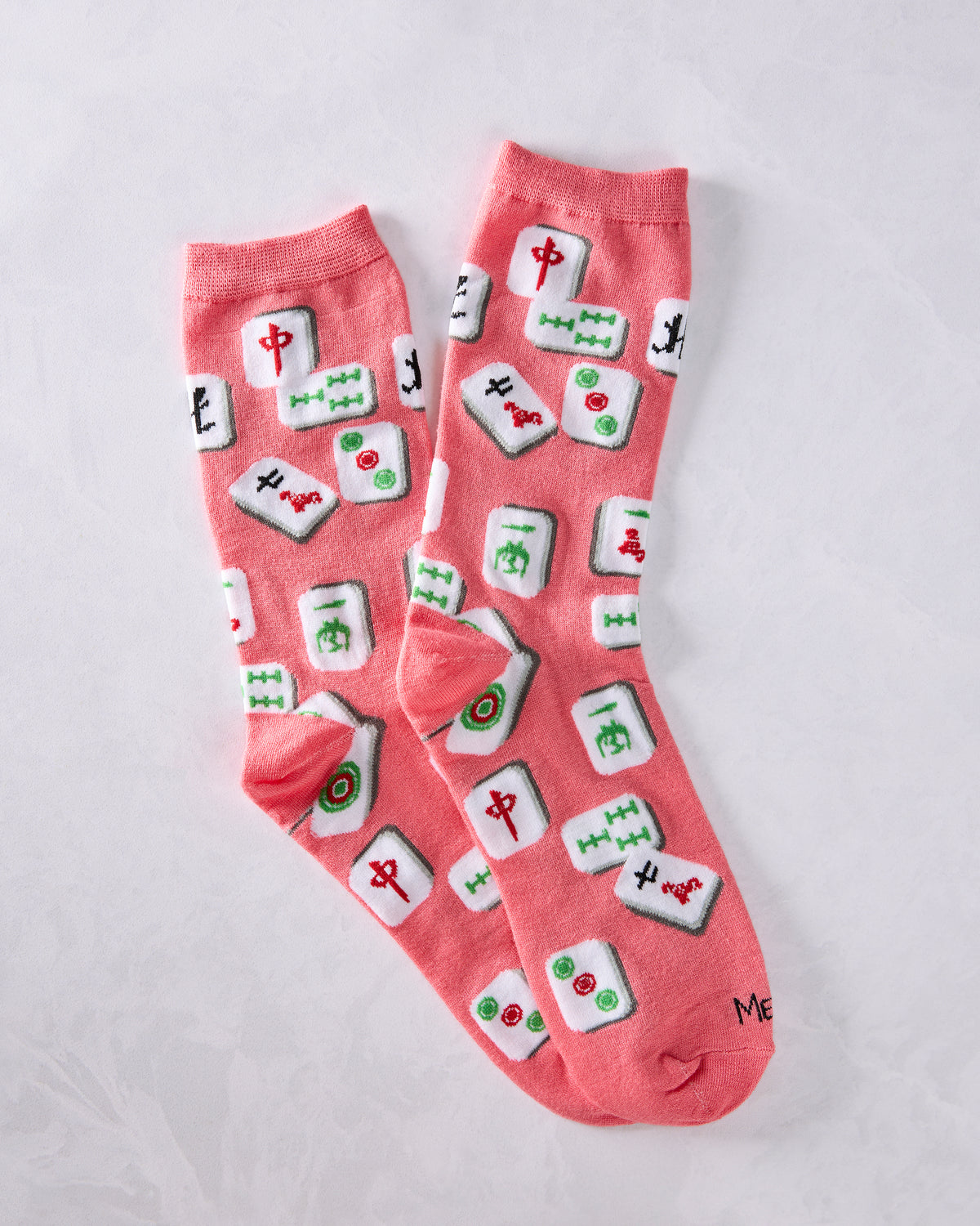Pair of pink crew socks covered with colorful mahjong tile designs.