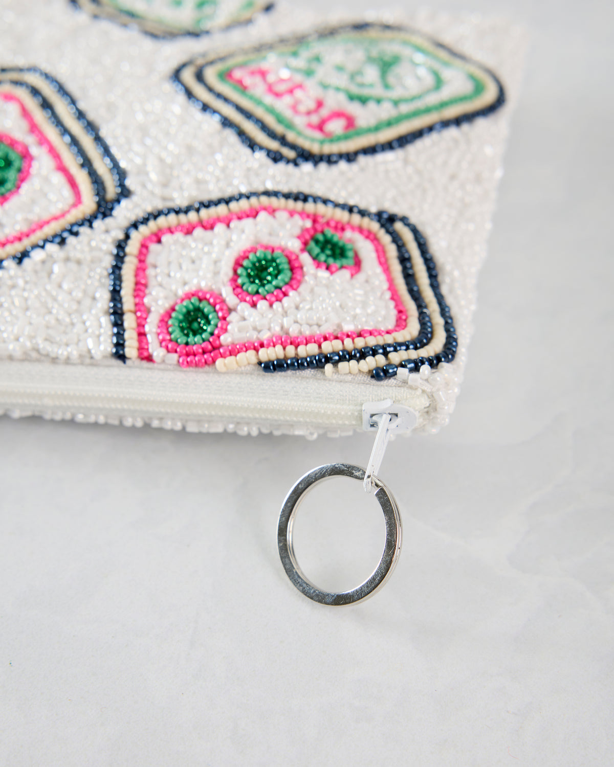 Close-up of the Mahjong coin purse corner showing the zipper, silver key ring, and colorful beaded tile motifs.