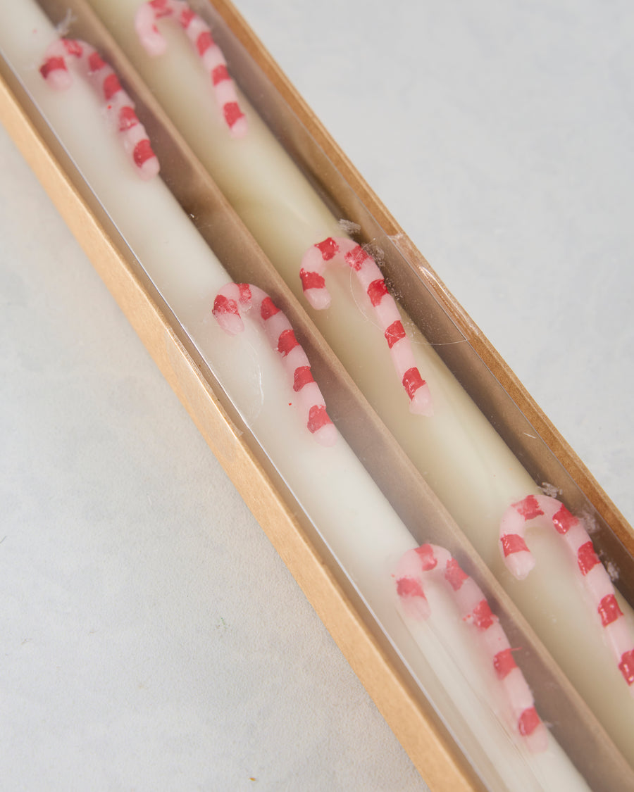 Close-up of white candles in a box decorated with pink and red candy-cane stripes.