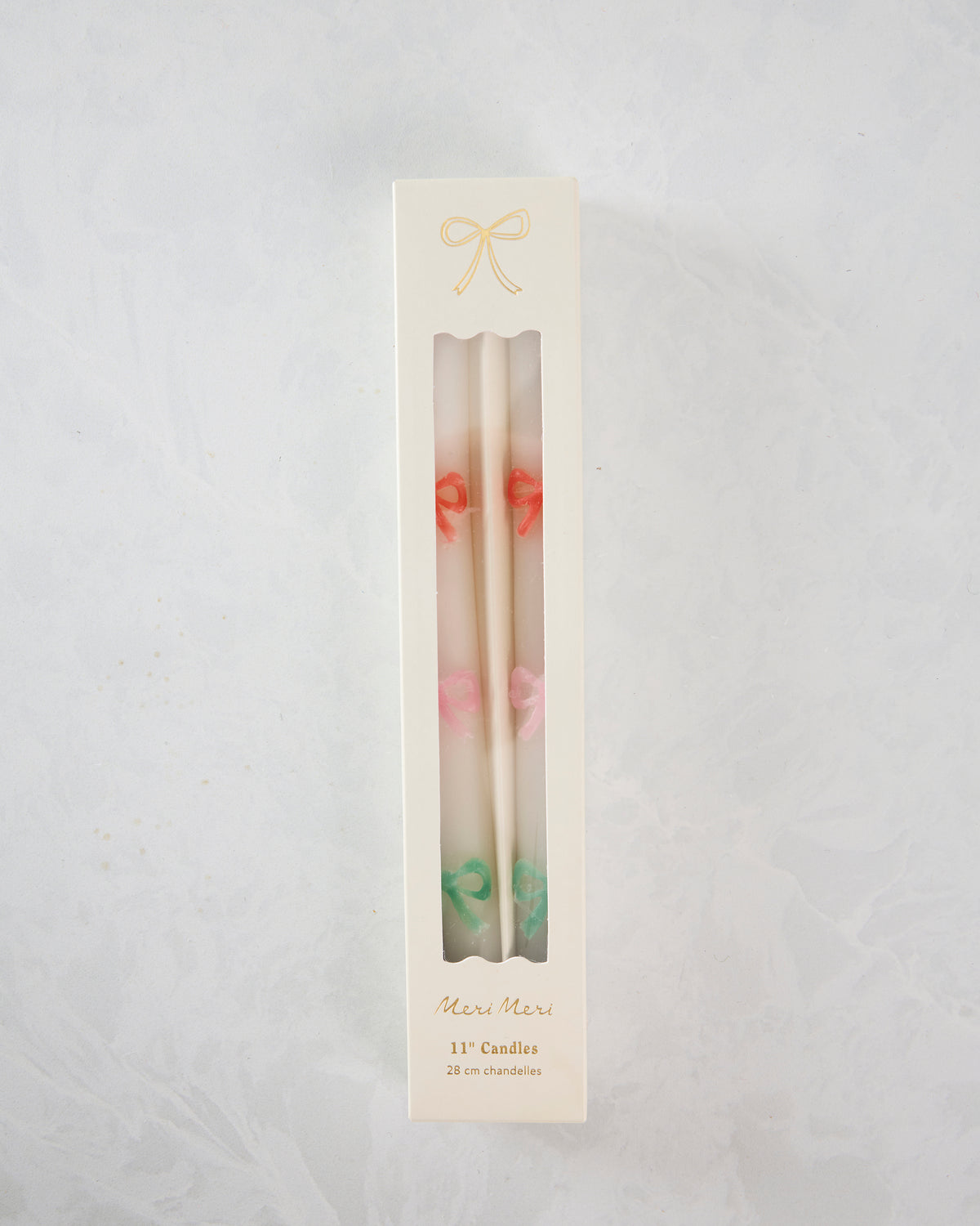 Boxed set of white taper candles with orange, pink, and green bow details; packaging reads “Meri Meri,” “11” Candles,” and “28 cm chandelles.”