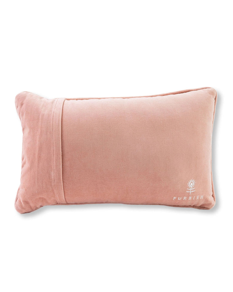 Reverse side of a rectangular pale pink pillow with a Furbish logo in the lower-right corner.