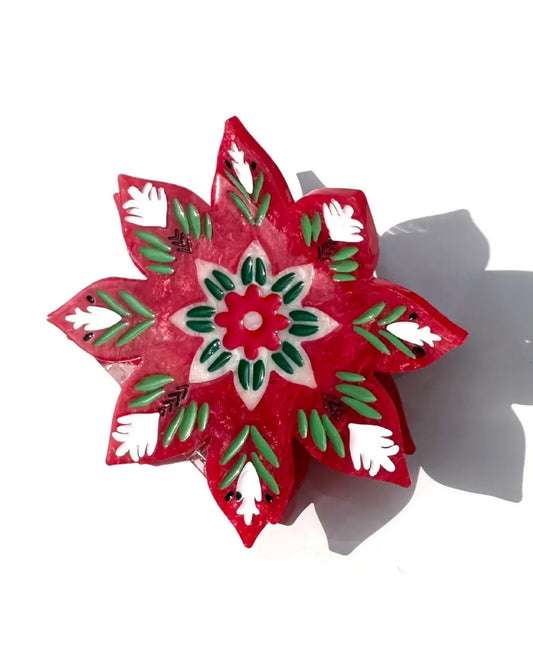 Close-up of the red, green, and white Christmas flower claw clip, showing its painted floral design.