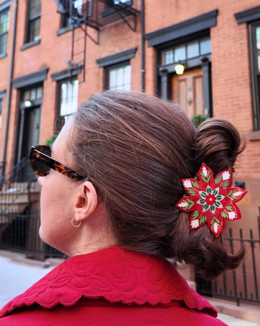 Christmas flower claw clip securing a bun, shown from the side.