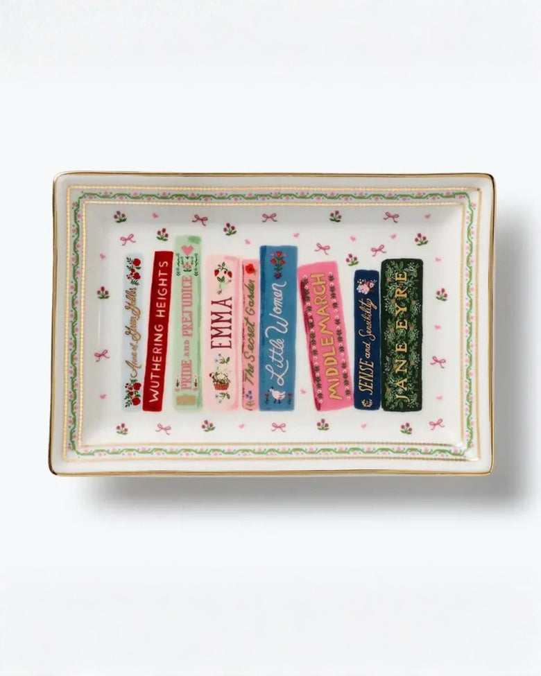 Rectangular porcelain catchall tray with a floral border and illustrated book spines, including Wuthering Heights, Pride and Prejudice, Emma, Little Women, Middlemarch, Sense and Sensibility, and Jane Eyre.