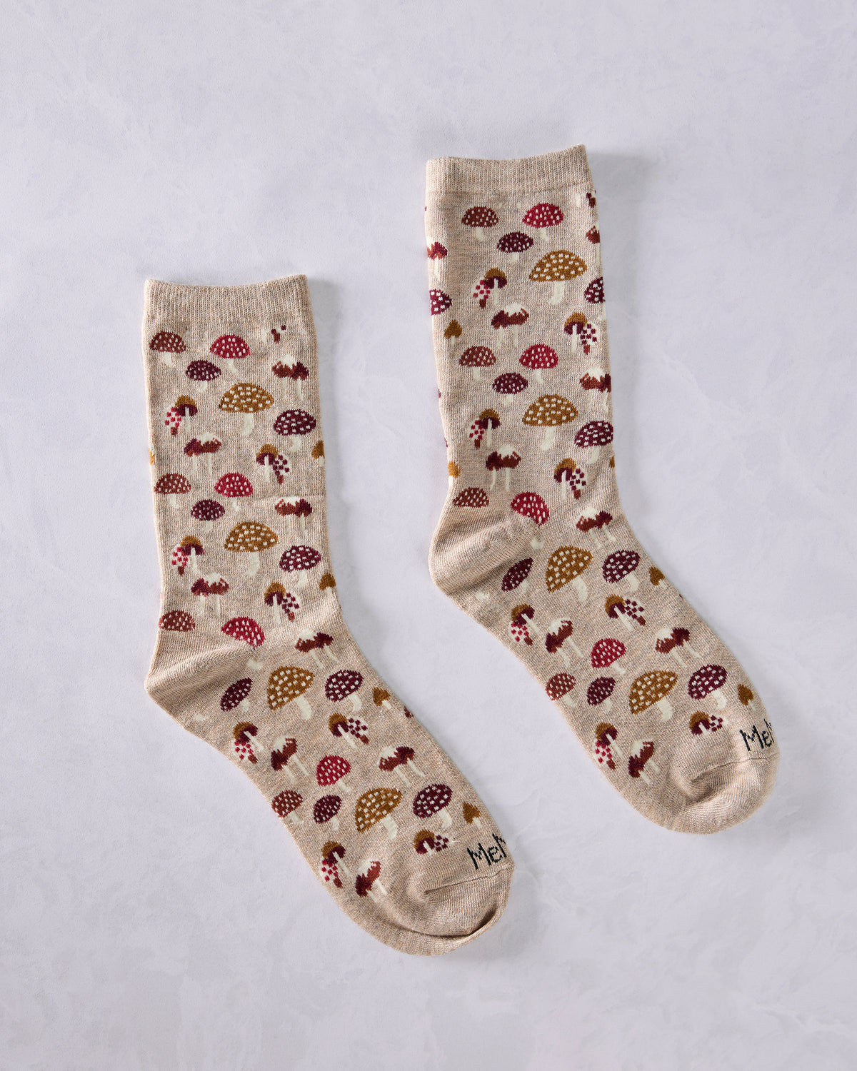 Pair of tan crew socks laid separately, featuring a repeating mushroom pattern.