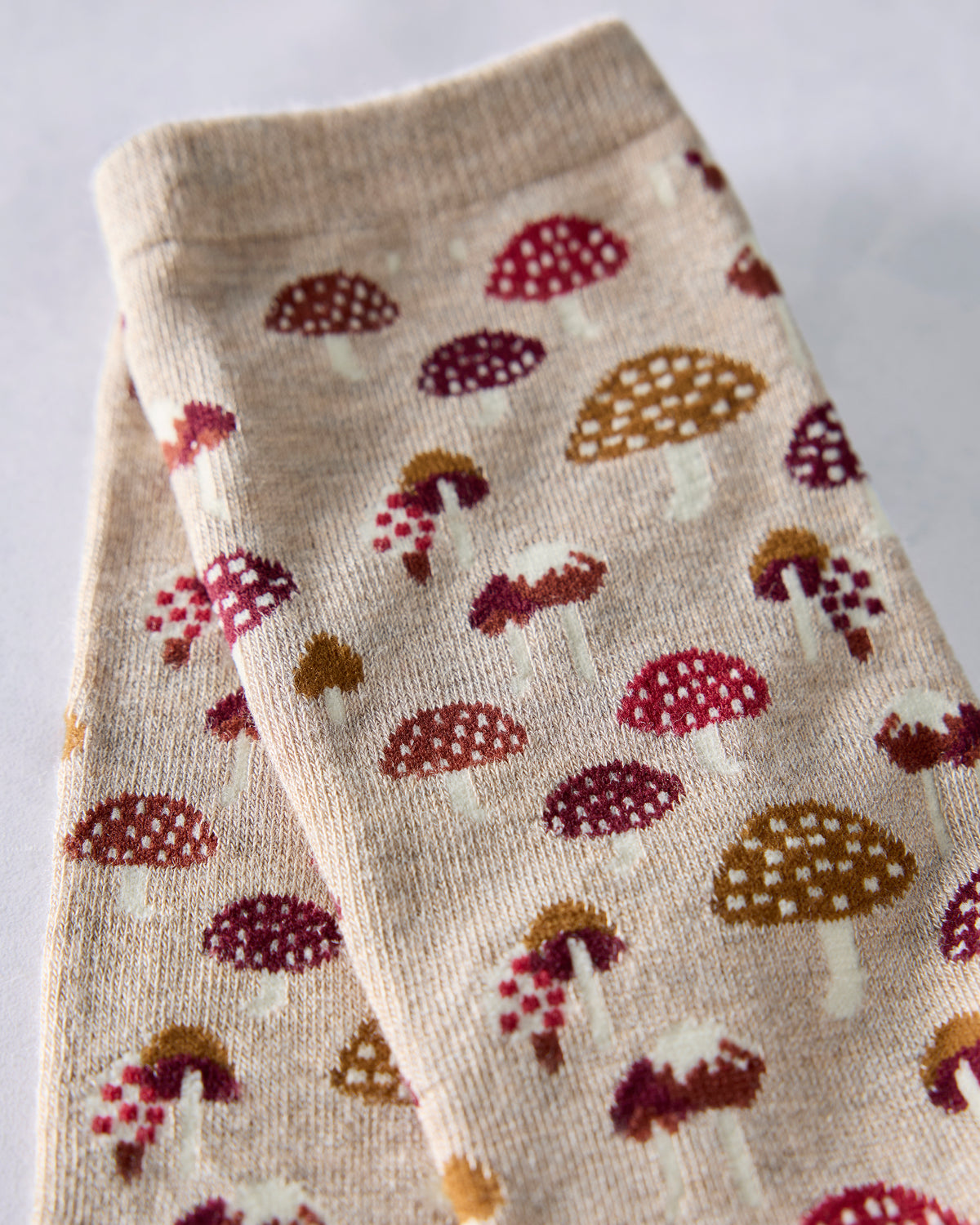 Close-up of the tan sock fabric showing the repeated mushroom print.
