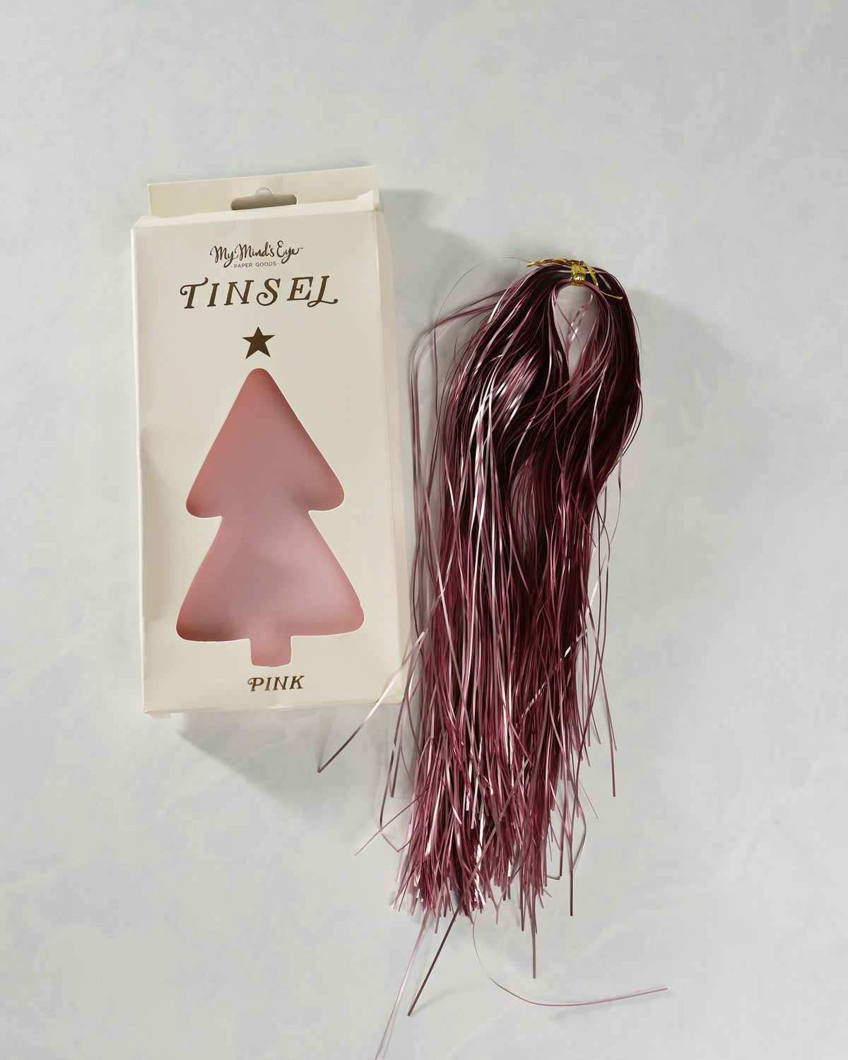 Package labeled Pink Tinsel beside a bundled length of pink metallic tinsel strands.