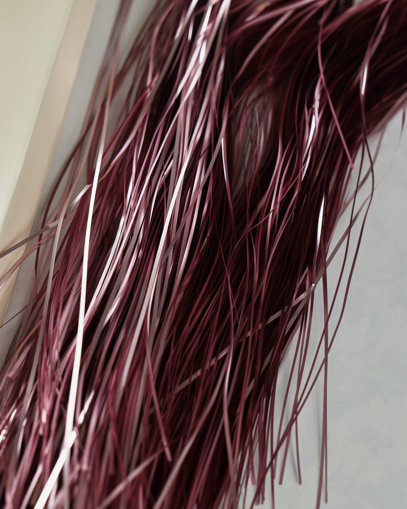 Close-up of thin pink metallic tinsel strands showing varied reflective highlights.