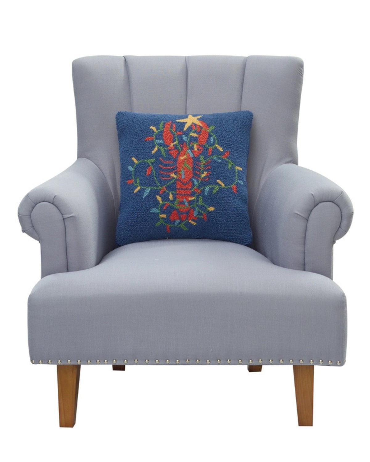 Navy lobster-design pillow shown resting against a light gray armchair.