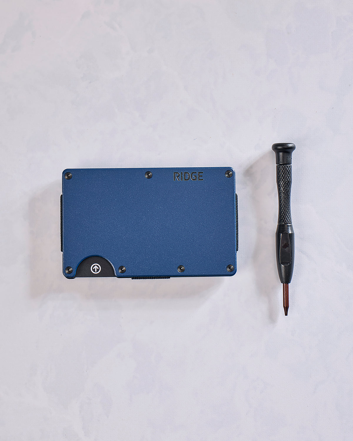 Navy Ridge wallet shown beside a small screwdriver, with a thumb notch and screws visible on the wallet.