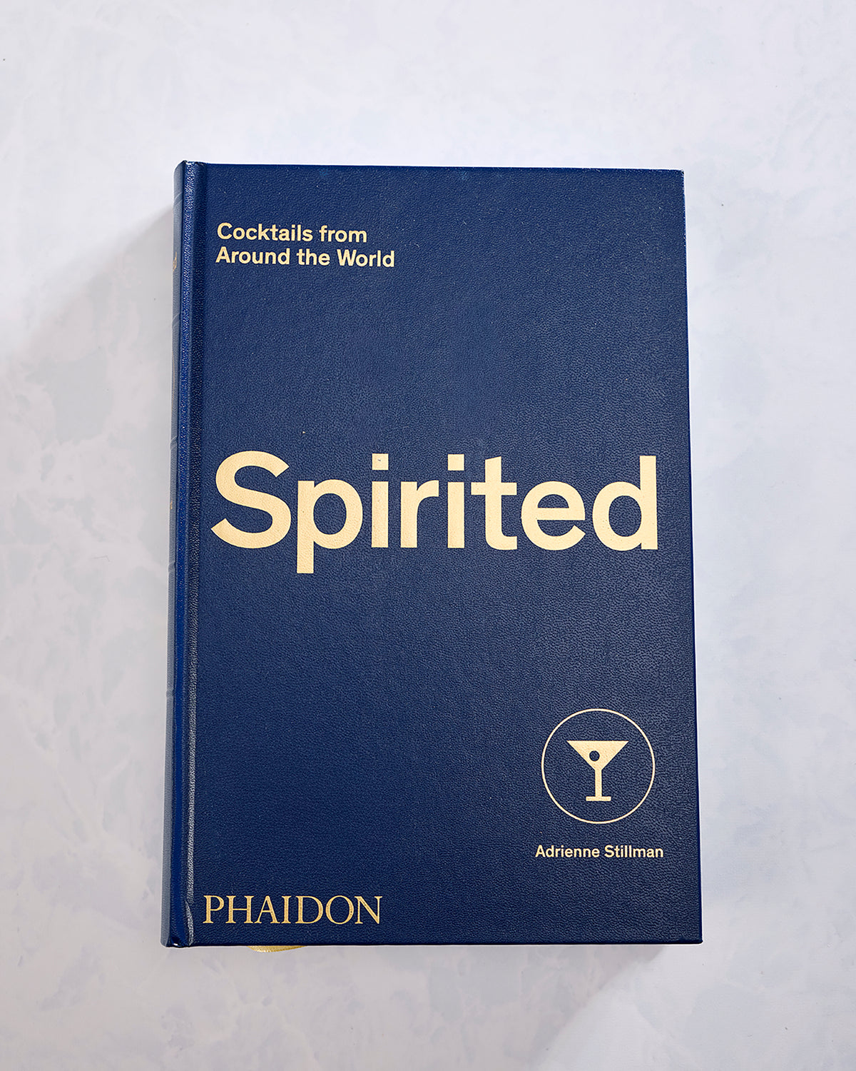 Front cover of the navy hardcover book Spirited: Cocktails from Around the World by Adrienne Stillman, published by Phaidon.