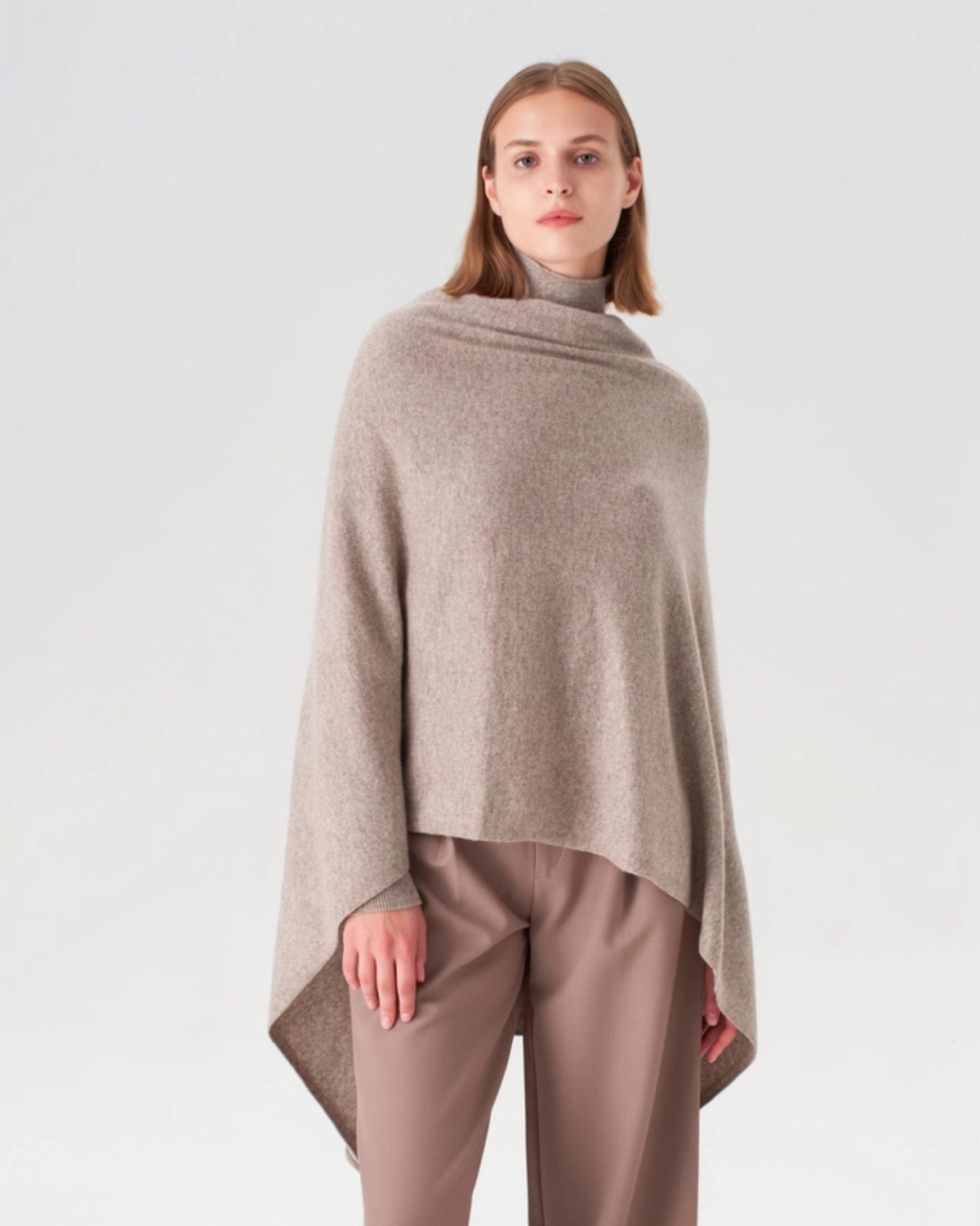 Front view of an oatmeal cashmere travel wrap draped over a model's shoulders, with wide pointed ends hanging at the sides.