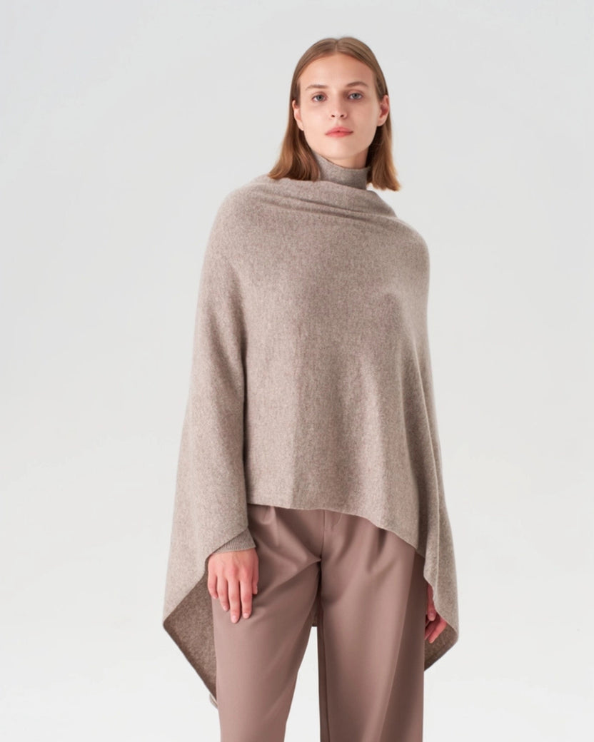 Front view of an oatmeal cashmere travel wrap draped over a model's shoulders, with wide pointed ends hanging at the sides.