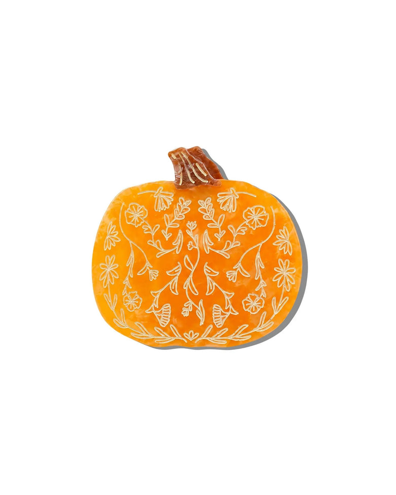 Front view of an orange pumpkin-shaped claw hair clip with an outlined floral pattern.
