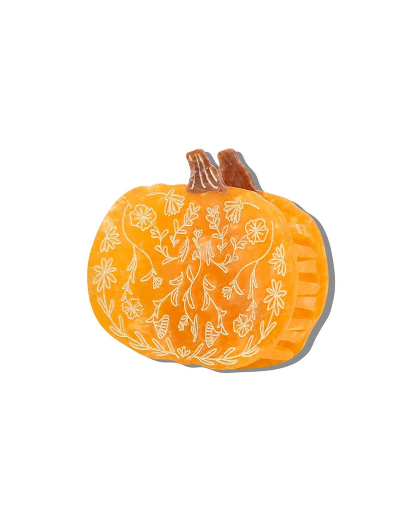 Angled side view of the orange pumpkin-shaped claw hair clip, showing its interlocking teeth and floral pattern.