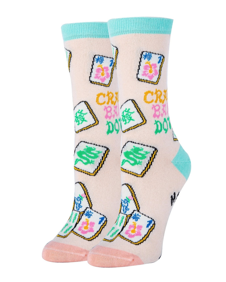 Pair of pale pink Mahjong-themed socks displayed upright, showing colorful tile illustrations, aqua cuffs and heels, and pink toes.